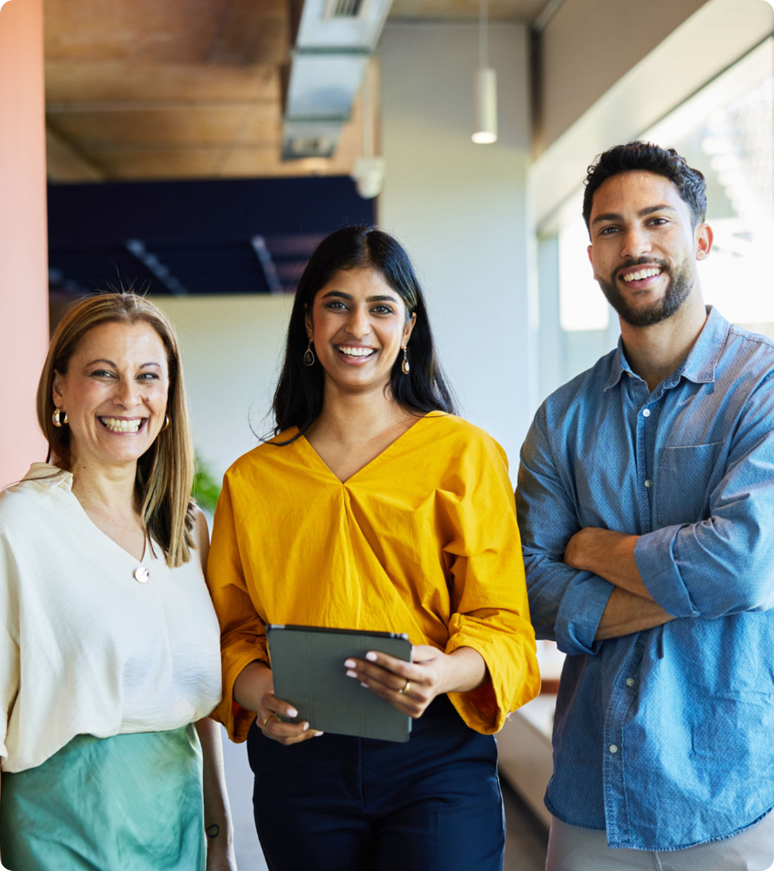 Three people smiling in an office setting.